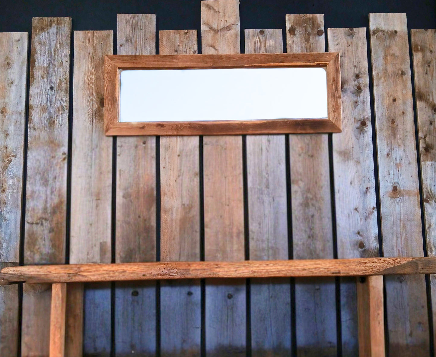Rustic reclaimed living space, featuring a wide solid oak mirror created from reclaimed wood, a rustic solid oak vanity. Complemented by micro cement walls and oak doors. The space is styled in a farmhouse-industrial spirit with soft brut details, and a reclaimed scaffolding plank accent wall.