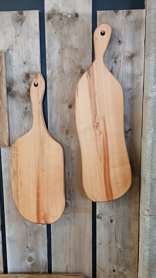 Two unique French cherry wood cheese boards or serving boards shown hanging on a reclaimed wood backdrop. 