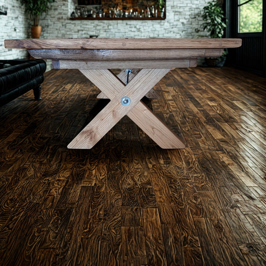 Handcrafted solid French Oak coffee table using reclaimed wood and recycled materials, set in an industrial style living room with dark parquet flooring, large window space and black leather furniture.