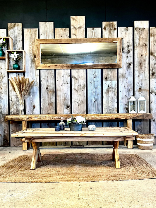 Rustic living room collection crafted from reclaimed oak, featuring a wide mirror, console table, and coffee table. Complemented by reclaimed chestnut box shelves and decorative reclaimed pine scaffolding planks. The space is styled in a boho-industrial spirit with pampas leaves, soft bohemian accents, and a cement floor.