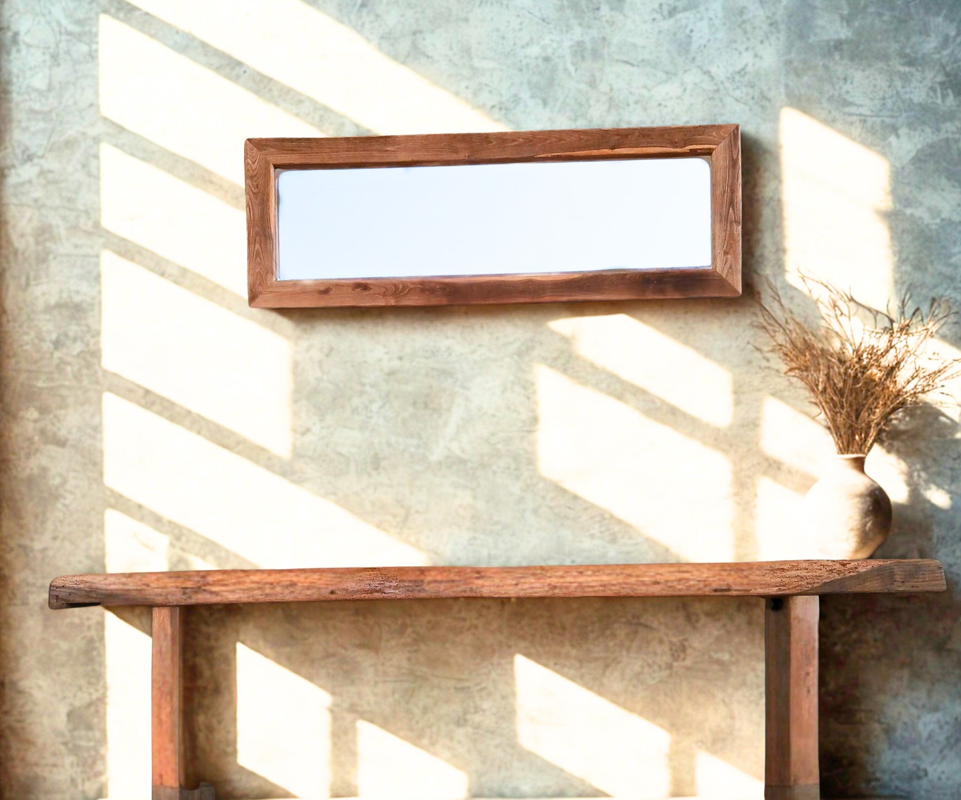 Rustic living room conceptual lifestyle design, featuring our wide solid oak mirror created from reclaimed wood and our rustic solid oak console table created from an old carpenter's workbench. Complemented by micro cement walls and a ceramic vase with dried stems and leaves. The space is styled in a soft, earthy spirit with soft bohemian accents.