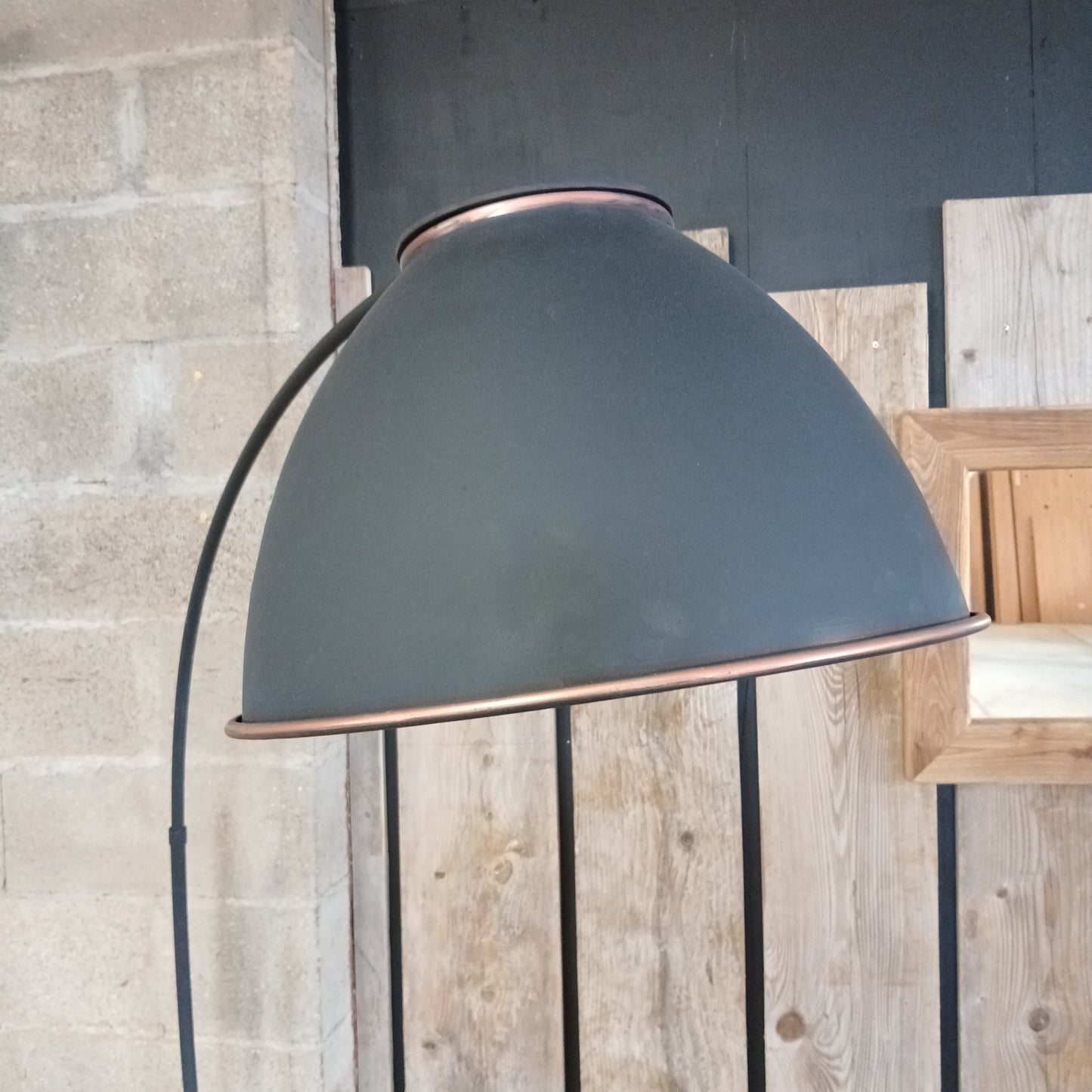Angoulême industrial standing lamp with reclaimed aluminium shade in copper and satin black, featuring curved black stand, styled with scaffolding planks, handmade in France.