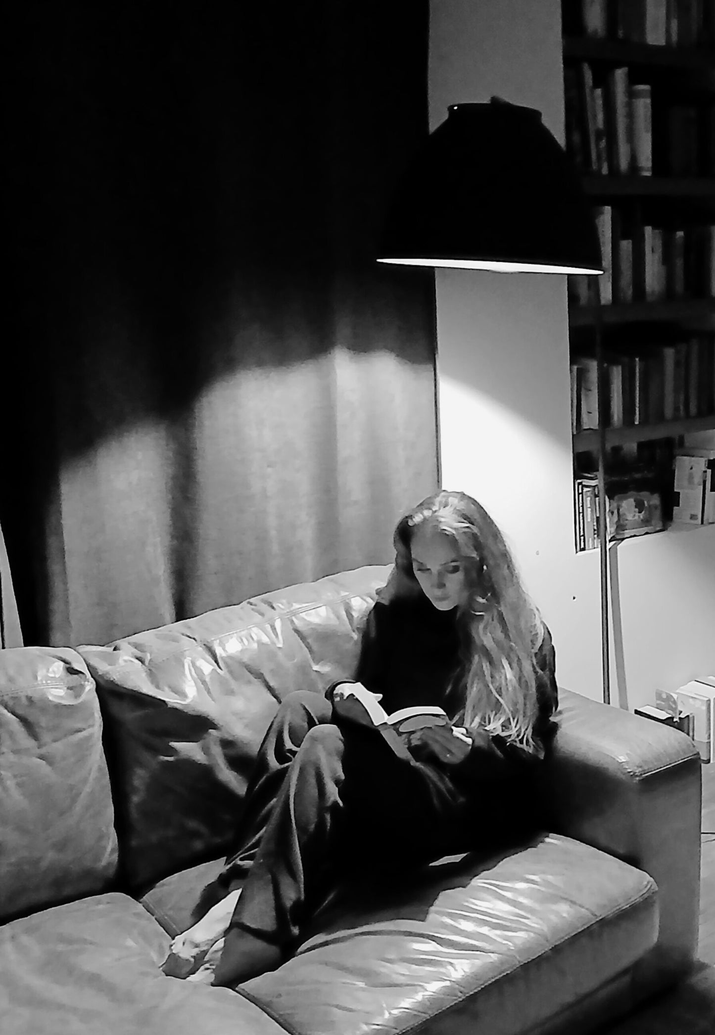 Angoulême industrial floor lamp in living room setting, black and white, showing low-voltage warm light over leather sofa, handmade in France.