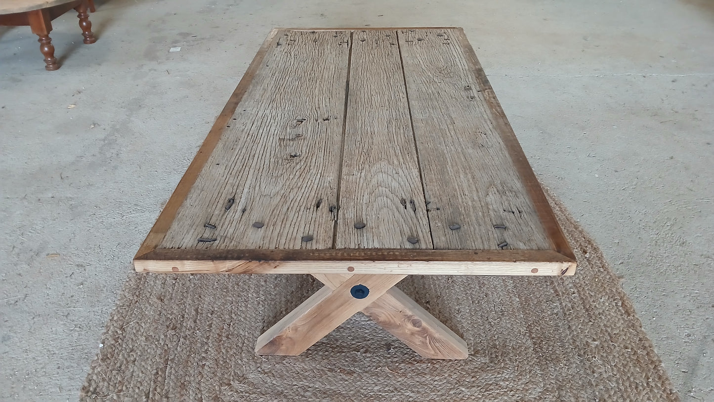 Top view of the Lisonne reclaimed French oak coffee table, showing rugged surface with original nail heads and elegant X-shaped farmhouse legs, handcrafted in France.