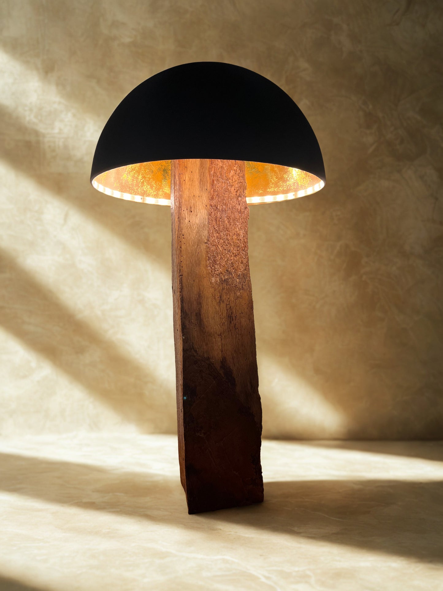 Solid oak mushroom floor lamp with matte black and copper shade. Warm white LED illuminates the copper interior, casting a soft, glowing light.
