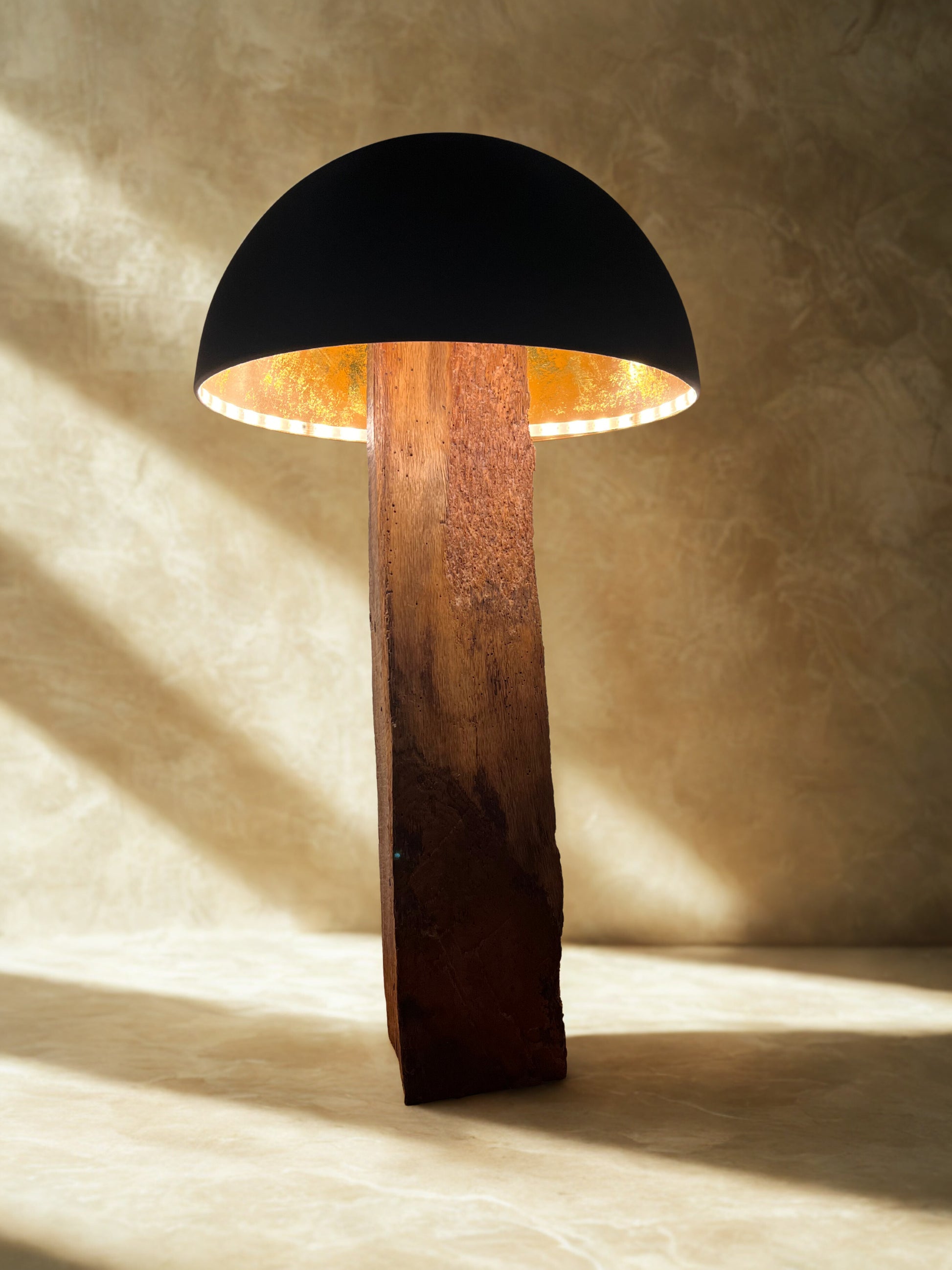Solid oak mushroom floor lamp with matte black and copper shade. Warm white LED illuminates the copper interior, casting a soft, glowing light.