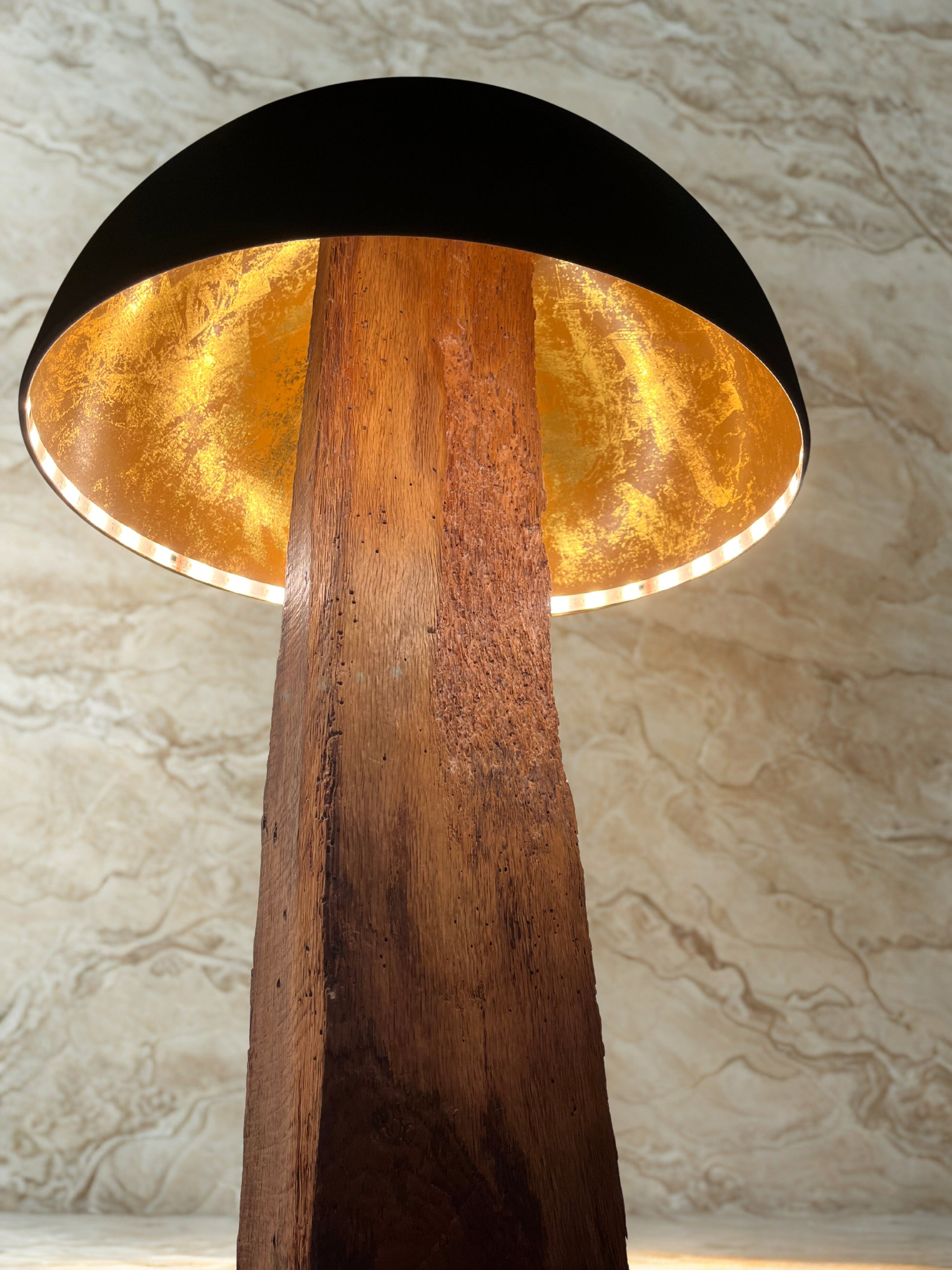 View of the solid oak mushroom floor lamp looking up into the copper interior of a solid oak mushroom floor lamp. Warm white LED highlights the reflective copper, contrasting with the matte black exterior.